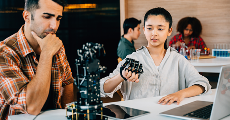 student and industry mentor working on robotic arm